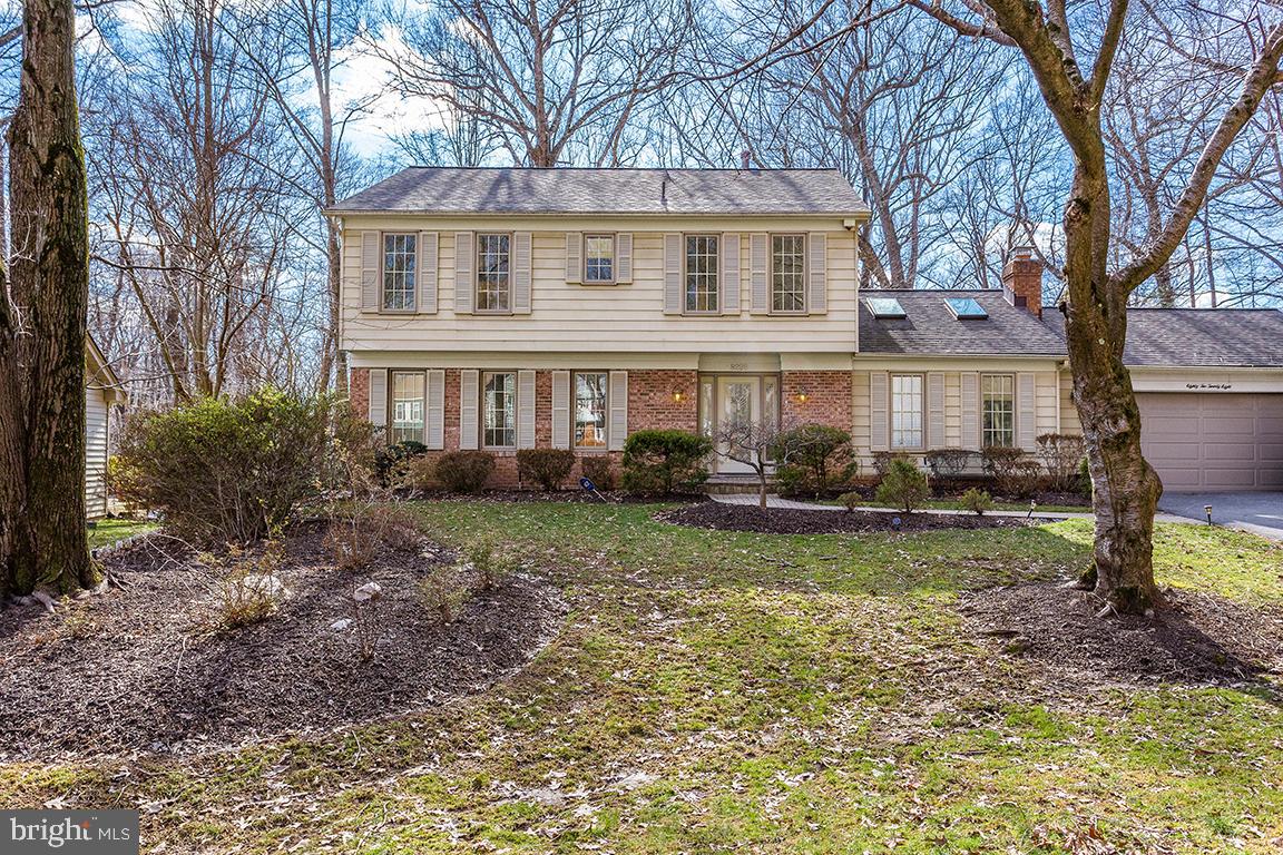 a view of a yard in front of a house with plants and large trees