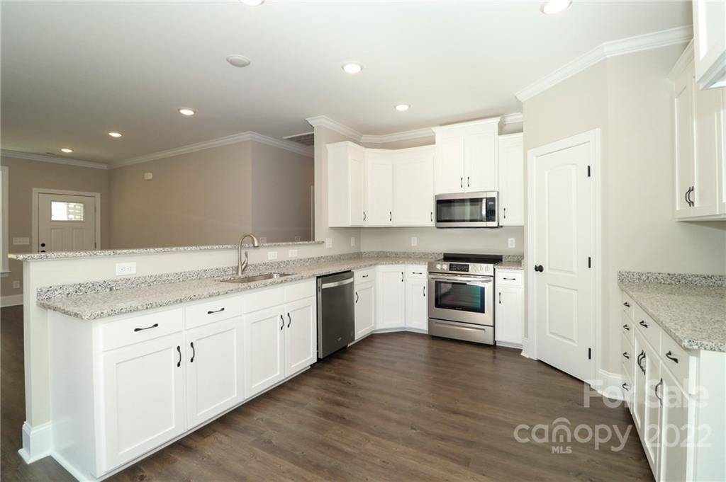 289 Ikerd Drive Southeast Concord, NC 28025 - Photo 9 of 24 a large kitchen with granite countertop a stove top oven a sink and dishwasher with wooden floor