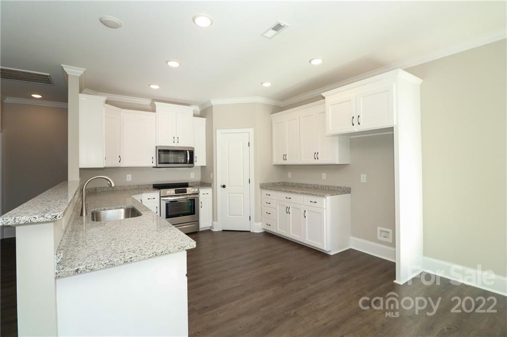 289 Ikerd Drive Southeast Concord, NC 28025 - Photo 10 of 24 a kitchen with granite countertop white cabinets and white appliances