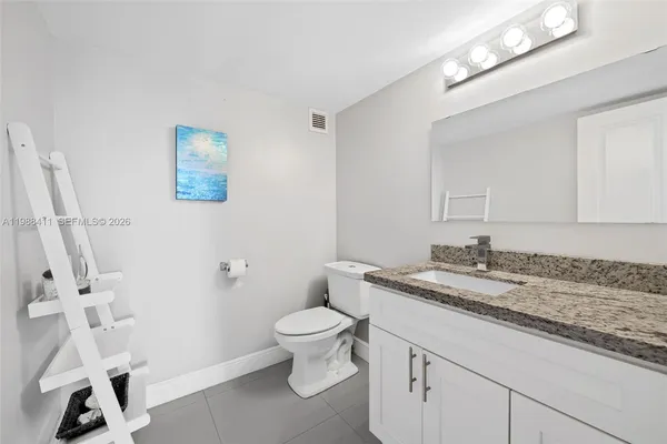 a bathroom with a granite countertop sink a toilet and a mirror
