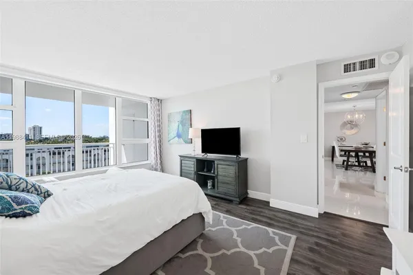a bedroom with a bed a large window and wooden floor