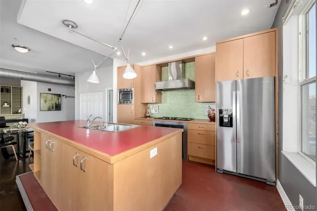 a kitchen with kitchen island stainless steel appliances a sink stove and refrigerator