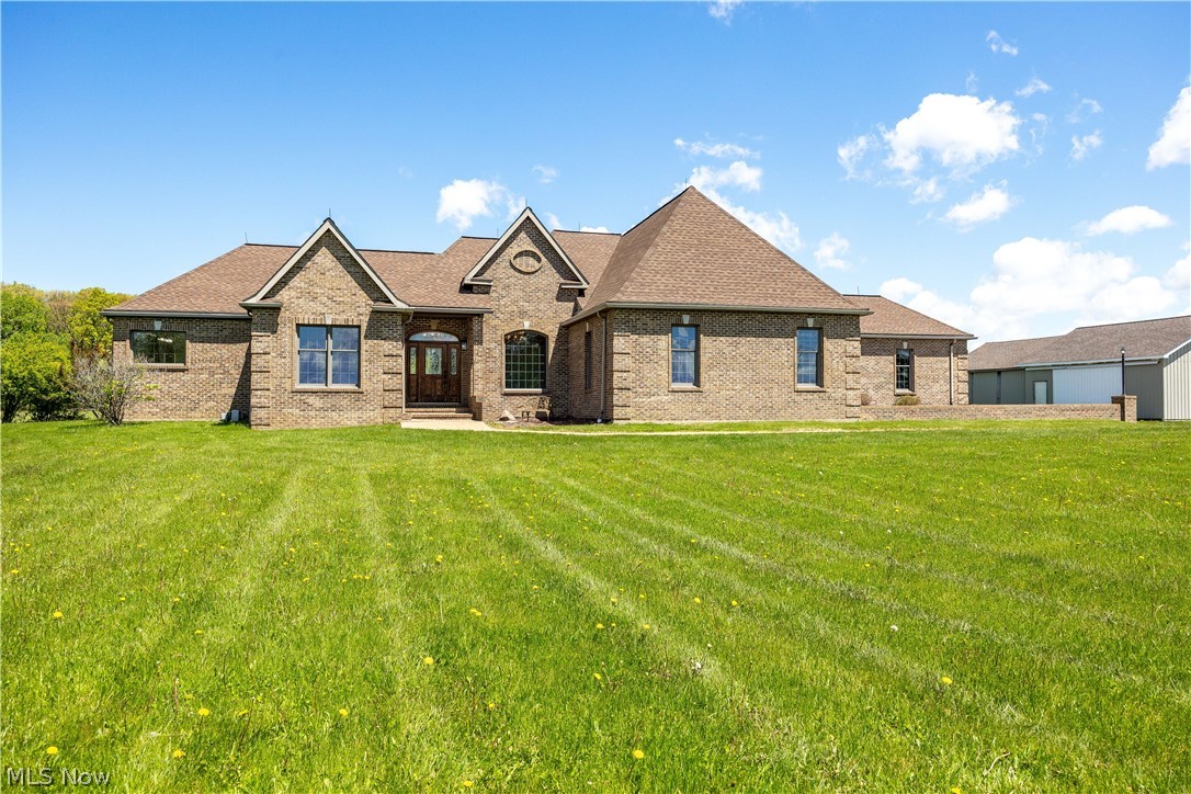 51488 Peck Wadsworth Road Wellington, OH 44090 - Photo 5 of 50 Brick exterior residence featuring a prominent gabled entry, symmetrical window placement, and a substantial shingle roof