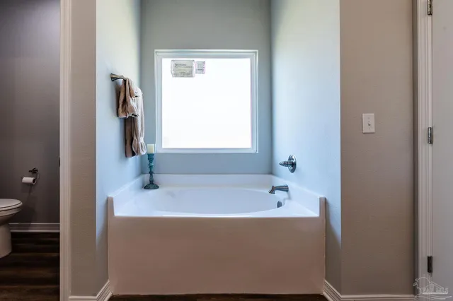 a view of a hallway with wooden floor and a bathroom