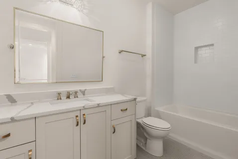 a bathroom with a toilet sink vanity tub and shower