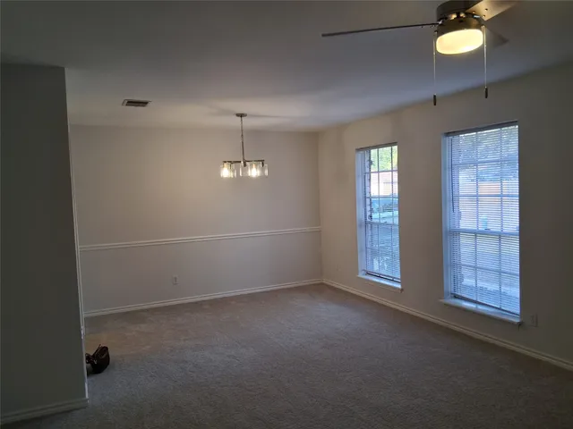 an empty room with windows and ceiling fan