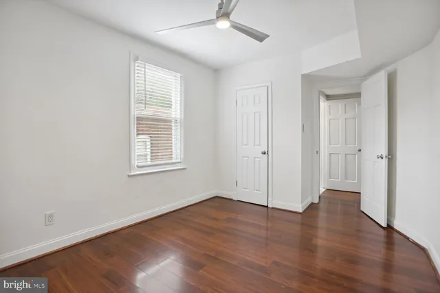 an empty room with wooden floor chandelier fan and windows
