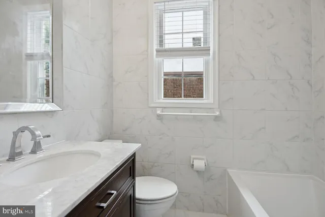 a bathroom with a sink toilet vanity and tub