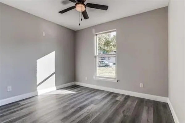 an empty room with wooden floor and ceiling fan