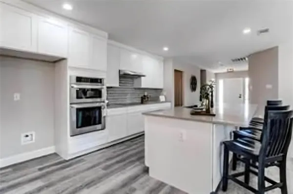 a kitchen with stainless steel appliances kitchen island granite countertop a stove a sink a refrigerator white cabinets and chairs