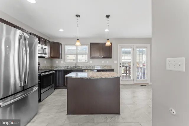 a large kitchen with kitchen island a counter top a stove a sink and a refrigerator