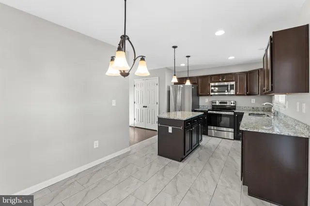 a large kitchen with stainless steel appliances kitchen island granite countertop a stove a sink a refrigerator and a microwave