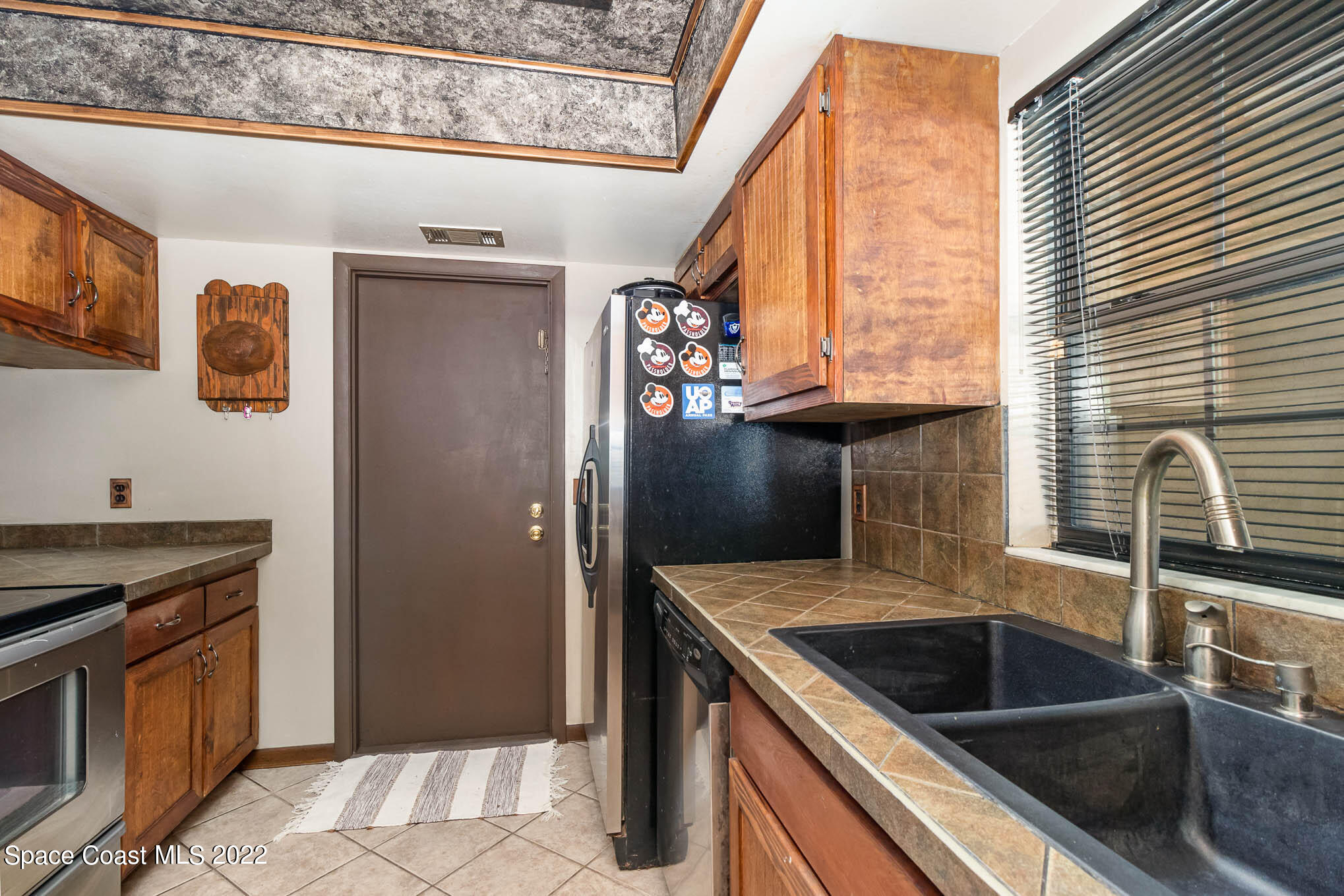 2539 Fulton Court Melbourne, FL 32935 - Photo 7 of 19 a kitchen with granite countertop a sink and a refrigerator