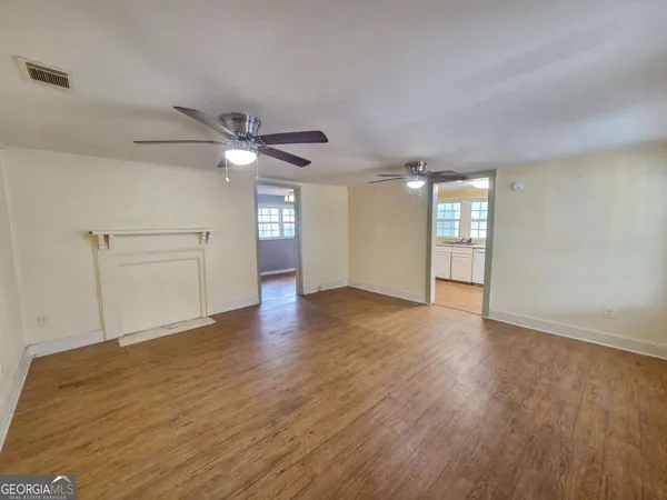 a view of an empty room with window and wooden floor