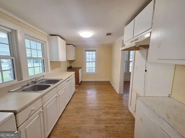 a large white kitchen with sink and windows