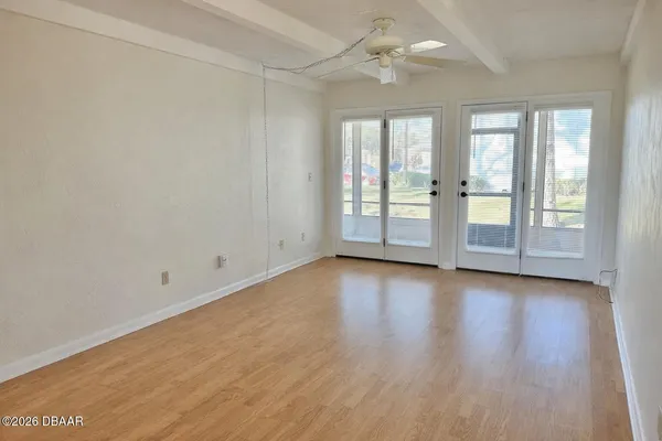 an empty room with wooden floor and windows with curtains