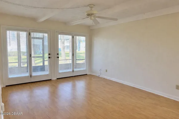 an empty room with wooden floor and windows with curtains