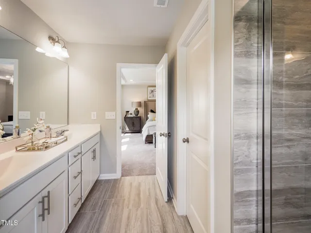 a spacious bathroom with a double vanity sink a mirror and shower