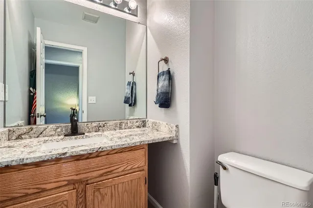 a bathroom with a granite countertop toilet sink and mirror