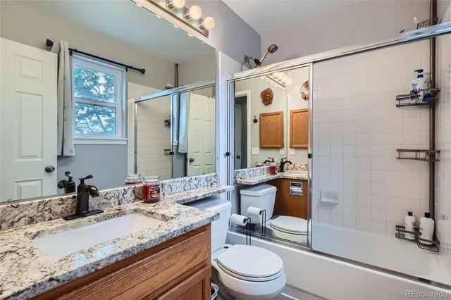 a bathroom with a granite countertop sink toilet mirror and shower
