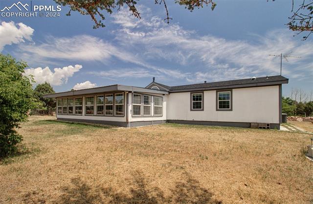 12825 Garrett Road Peyton, CO 80831 - Photo 5 of 47 Rear view of house with a sunroom and a lawn