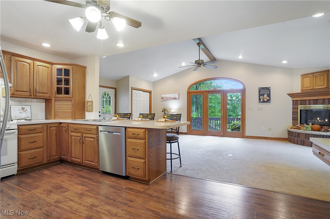 449 East Comet Road Clinton, OH 44216 - Photo 21 of 39 Kitchen with lofted ceiling with beams, a breakfast bar, kitchen peninsula, dark carpet, and stainless steel dishwasher