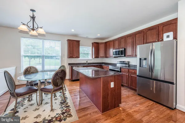 a kitchen with granite countertop a stove a sink a dining table and chairs