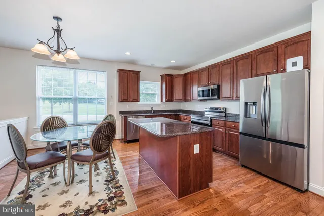 a kitchen with granite countertop a stove a sink a dining table and chairs