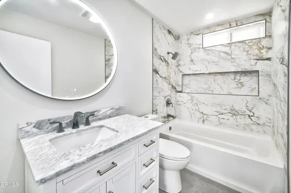 a bathroom with a granite countertop sink toilet and shower