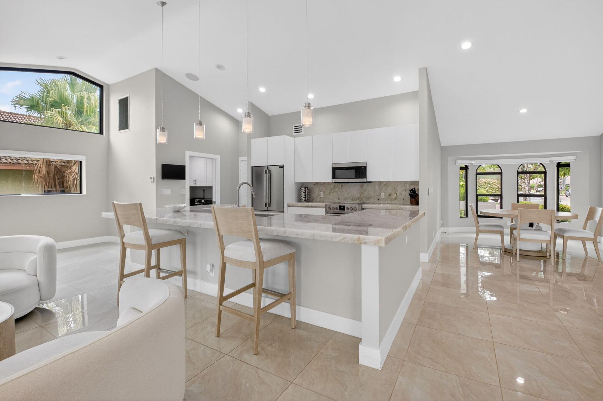 2871 Northwest 49th Street Boca Raton, FL 33434 - Photo 3 of 60 a kitchen with stainless steel appliances kitchen island granite countertop a stove a sink a dining table and chairs