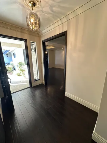 an empty room with wooden floor chandelier and windows