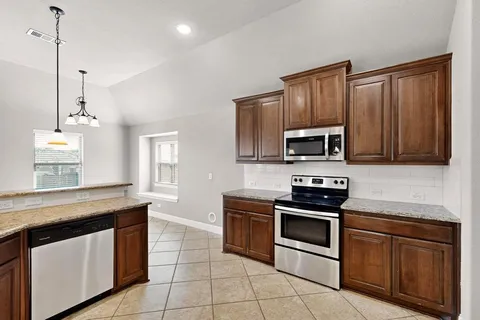 a kitchen with granite countertop a stove sink and microwave