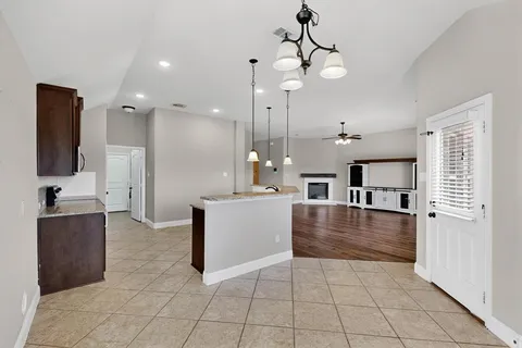 a large kitchen with kitchen island a stove a sink a refrigerator and a granite counter top