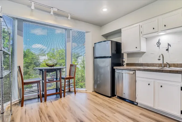 a kitchen with kitchen island wooden floors white cabinets and stainless steel appliances