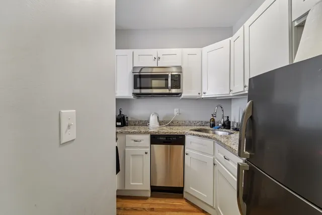 a kitchen with stainless steel appliances granite countertop white cabinets sink and a granite counter top