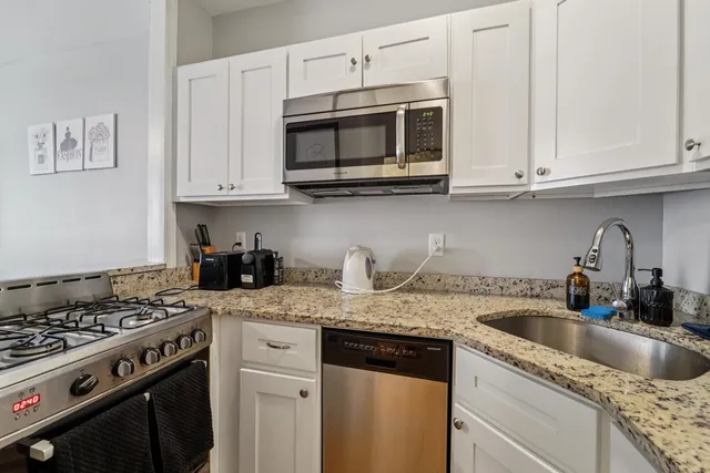 a kitchen with granite countertop white cabinets and stainless steel appliances