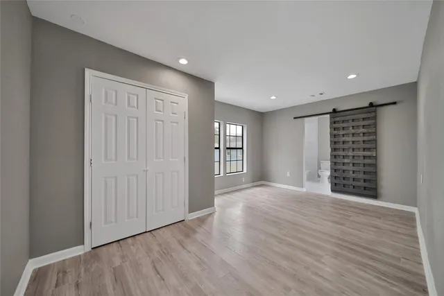 a view of an empty room with wooden floor and window