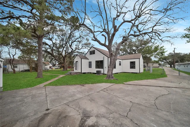 a view of a white house next to a yard and road