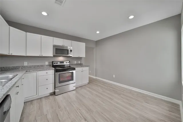 a kitchen with stainless steel appliances granite countertop a stove a sink and a microwave