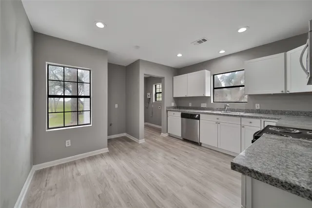 a kitchen with granite countertop a stove a sink and a refrigerator