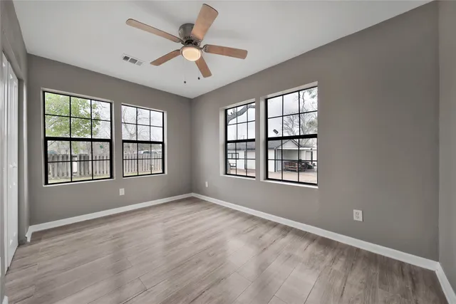 an empty room with wooden floor and windows
