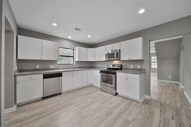 a kitchen with granite countertop white cabinets and stainless steel appliances
