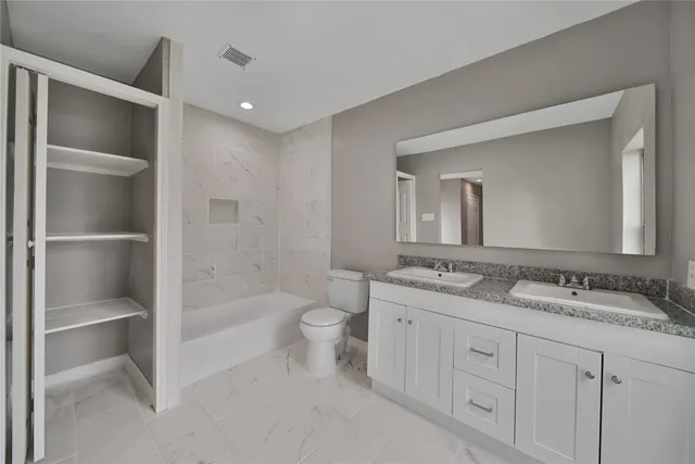 a bathroom with a granite countertop sink a toilet and a large mirror
