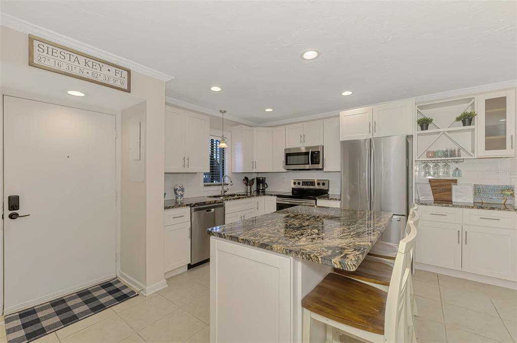 1612 Stickney Point Road, Unit 16121 Sarasota, FL 34231 - Photo 9 of 39 a kitchen with stainless steel appliances granite countertop a stove refrigerator and cabinets