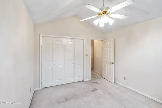 an empty room with chandelier fan and windows