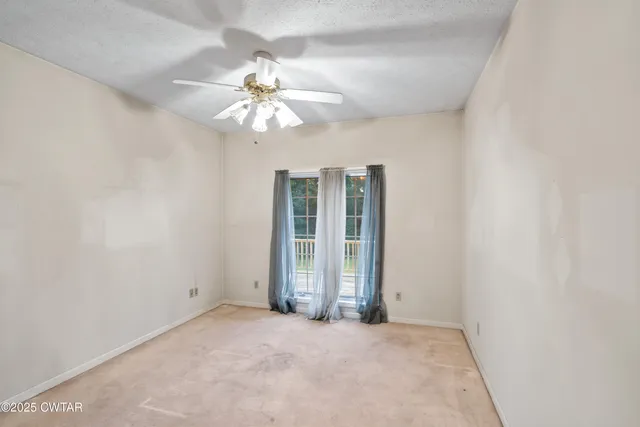 an empty room with fan and a chandelier fan
