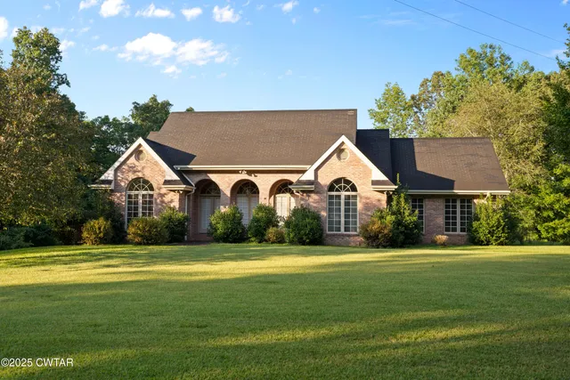 a view of a house with a big yard and large trees