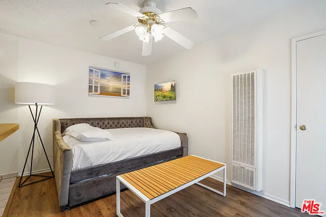 a bedroom with a bed a table and wooden floor