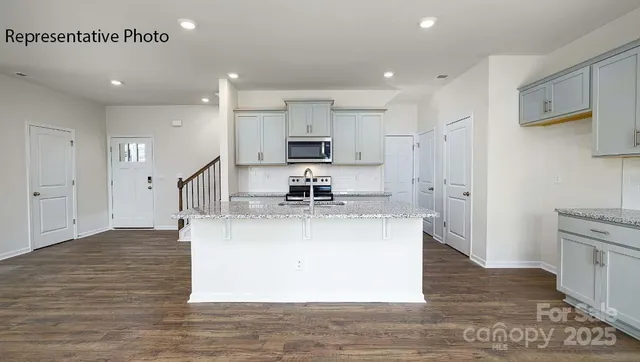 a view of kitchen with stainless steel appliances granite countertop a stove a sink and a refrigerator