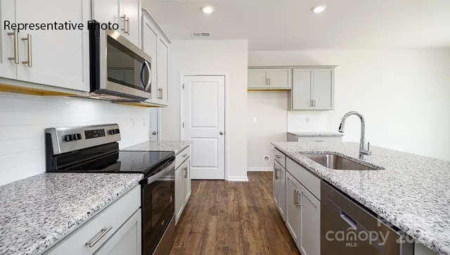 a kitchen with stainless steel appliances granite countertop a sink stove microwave and refrigerator